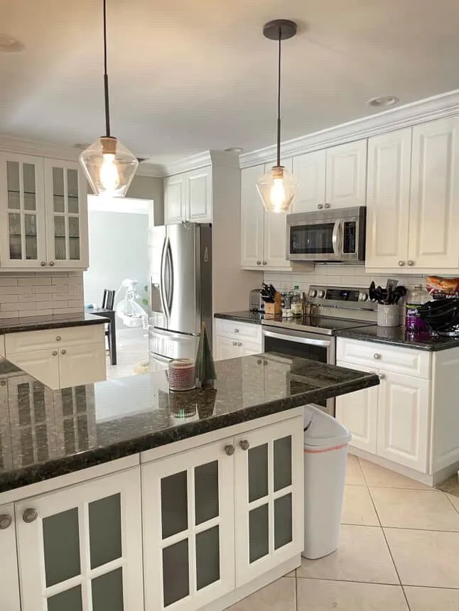 A kitchen with white cabinets, dark countertops, a central island, and stainless steel appliances.
