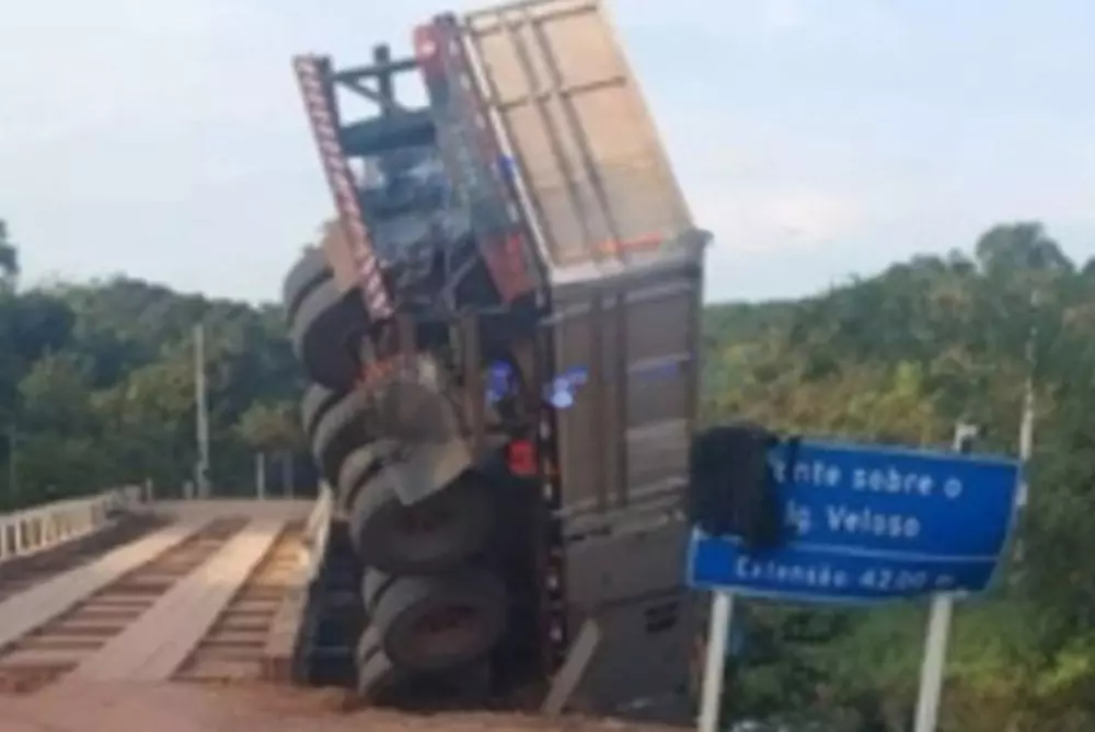 Carreta tomba e fica pendurada em ponte de madeira na BR-319