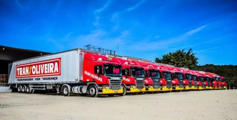 A foto mostra uma frota de caminhões Transoliveira