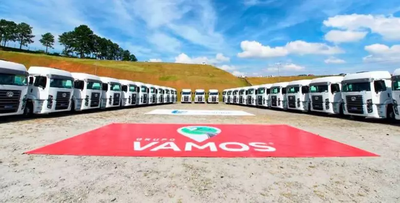 A foto mostra um pátio cheio de caminhões do Grupo Vamos