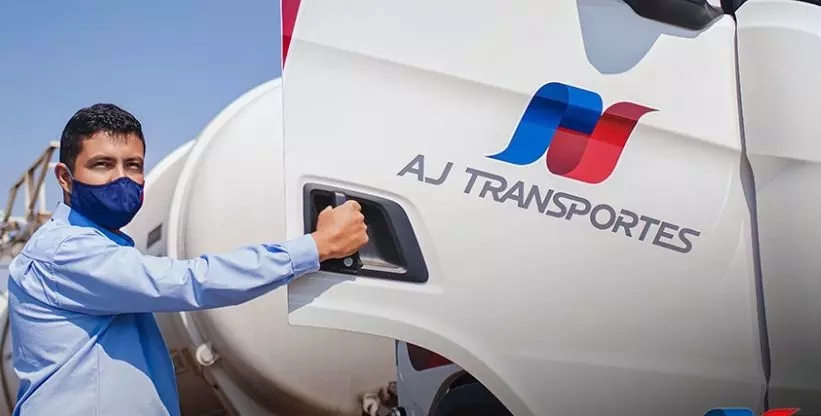 A foto mostra uma carreta e um motorista da AJ Transportes