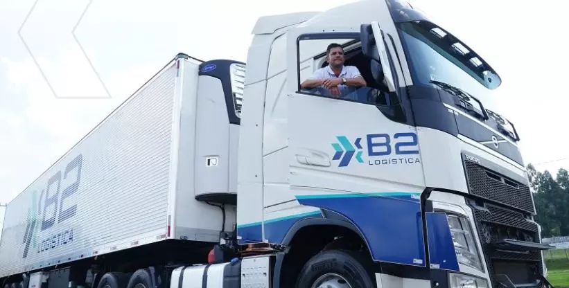 A foto mostra uma carreta da B2 Logística e um motorista