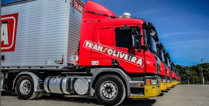 A foto mostra uma frota de carretas da Transoliveira