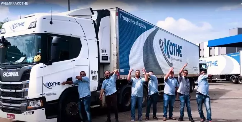 A foto mostra uma carreta da Kothe Transportes e vários motoristas fazendo sinal de vem para Kothe