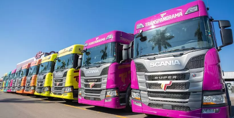 A foto mostra uma frota de caminhões Scania da Transpanorama