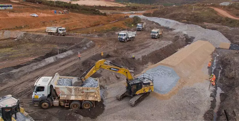 A foto mostra uma escavadeira carregando um caminhão da Construtora Terraço