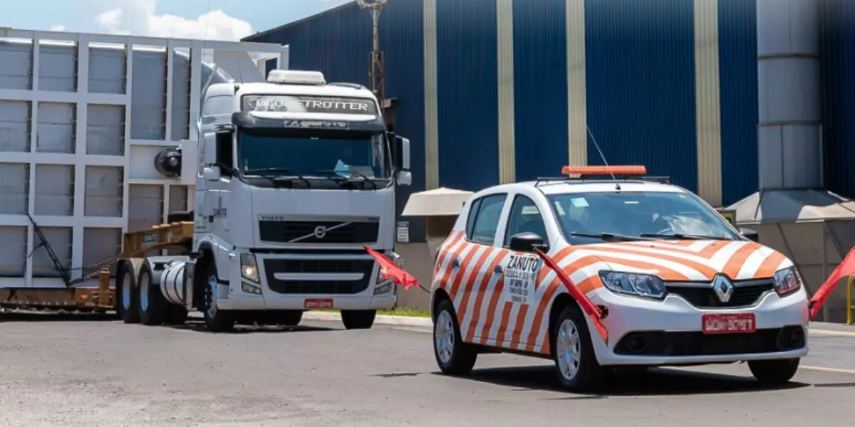 A foto mostra um carro fazendo Escolta na frente de uma carreta da Transpes