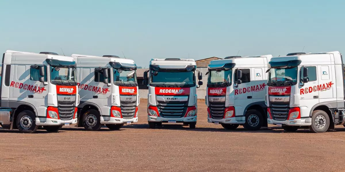 A foto mostra uma frota de caminhões da Rodomax Transportes