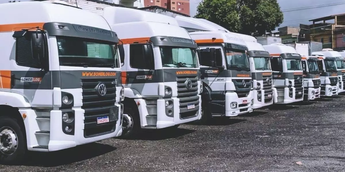 A foto mostra uma frota de caminhões da Somerlog Logística e Transportes