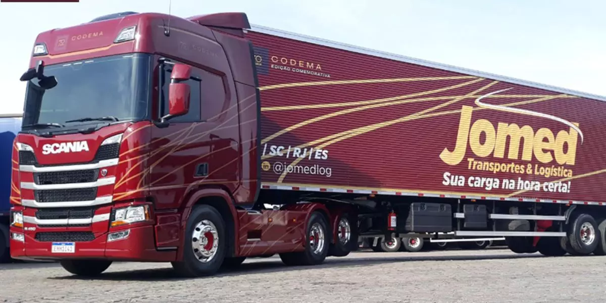 A foto mostra uma carreta da Jomed Transportes e Logística