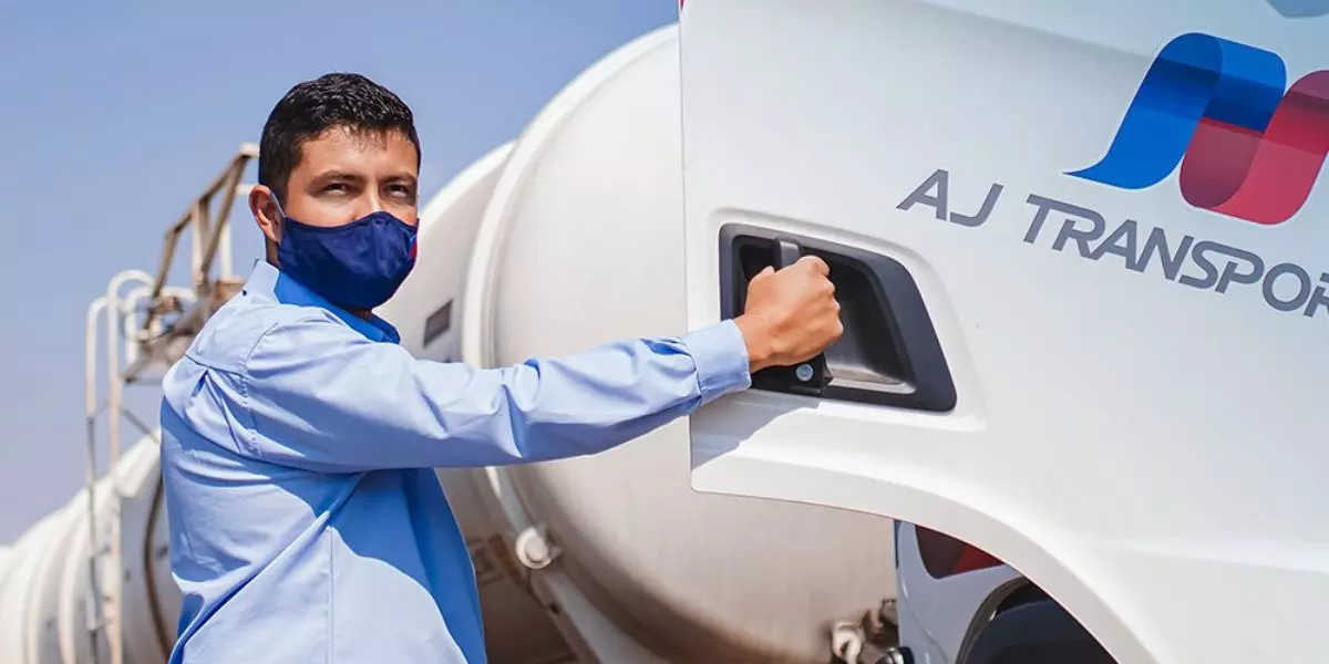 A foto mostra uma carreta e um motorista da AJ Transportes