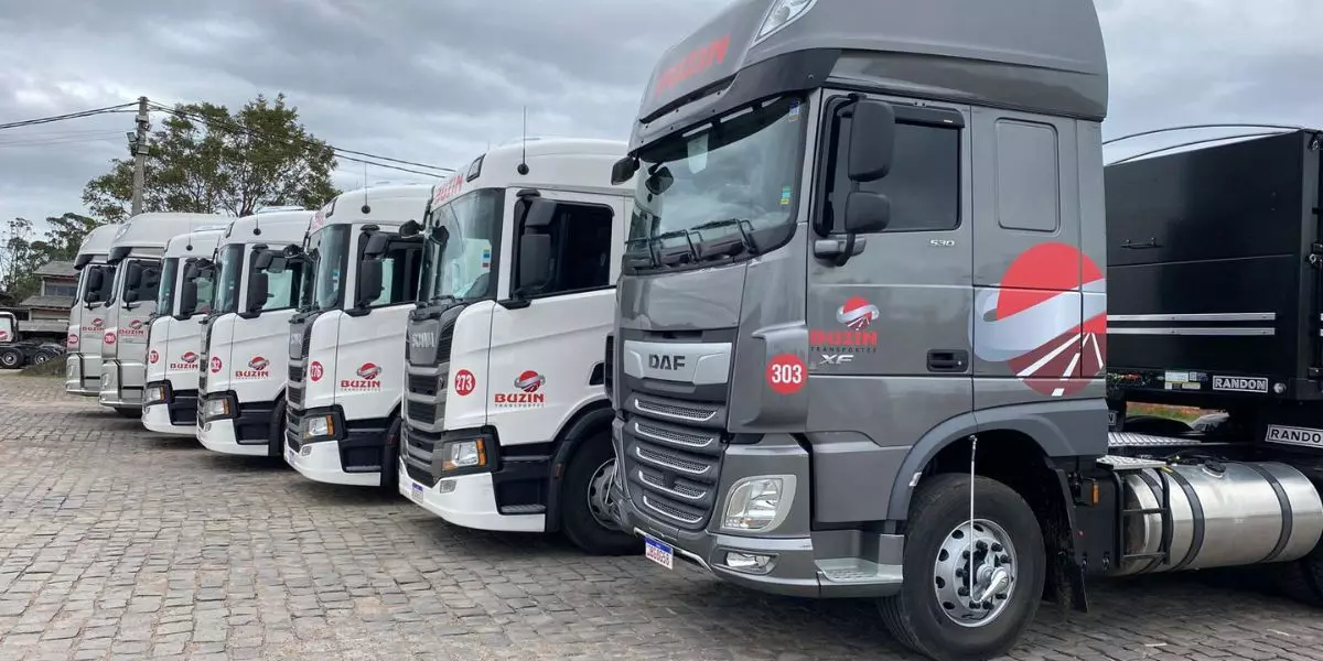 A foto mostra uma frota de caminhões da Buzin Transportes