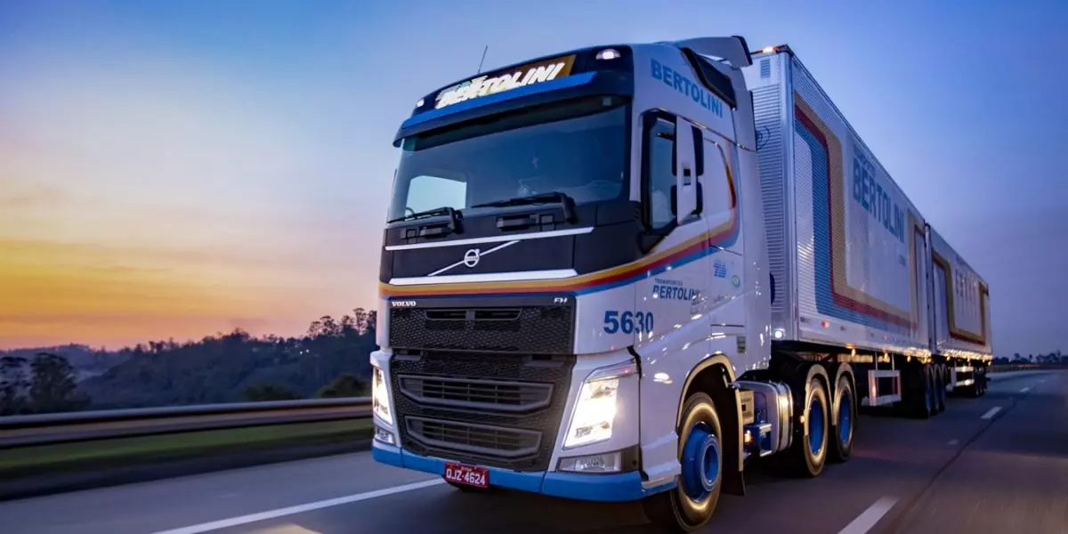 A foto mostra uma carreta azul e branca da Transportes Bertolini