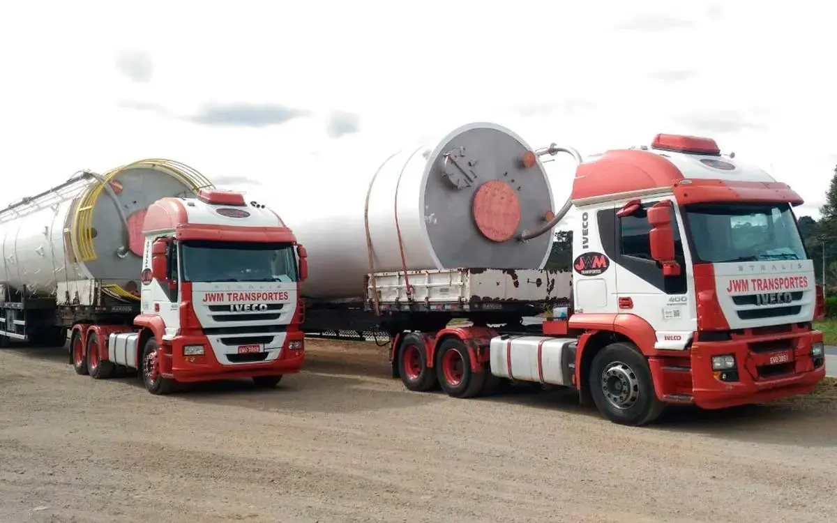 A foto mostra dois caminhões da JWM Transportes
