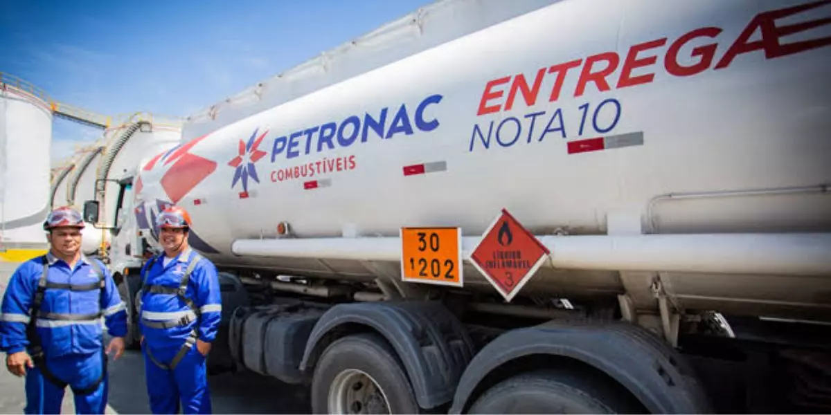 A foto mostra uma carreta e dois funcionários da Petronac