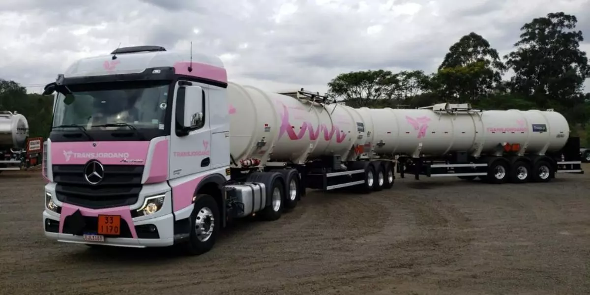 A foto mostra uma carreta branca e rosa da TransJordano