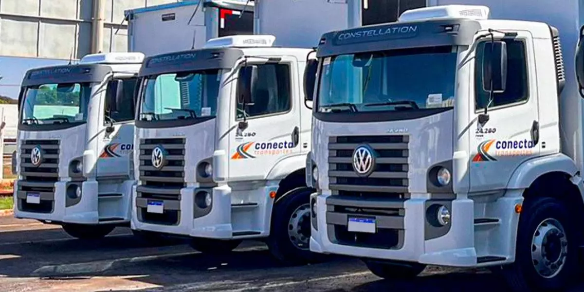 A foto mostra uma frota de caminhões da Conecta Transportes