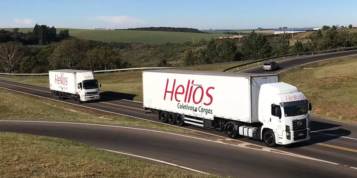 A foto mostra uma carreta e um caminhão da Helios Cargas