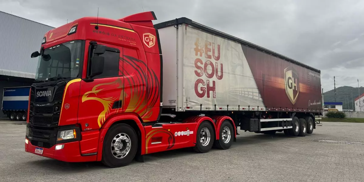 A foto mostra uma carreta vermelha da GH Transporte