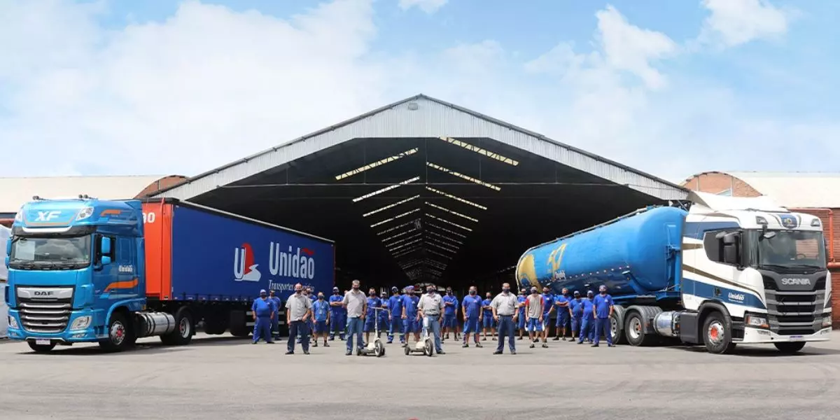 A foto mostra duas carretas e motoristas da Unidão Transportes e Logística