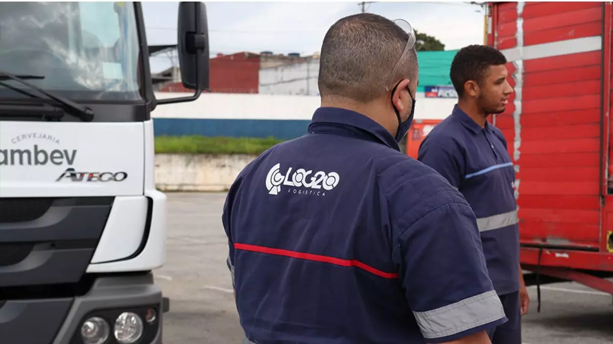 A foto mostra dois caminhões e dois motoristas da LOG20 Logística