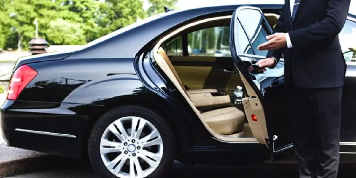 A foto mostra um carro e um motorista executivo do Grupo Bauminas