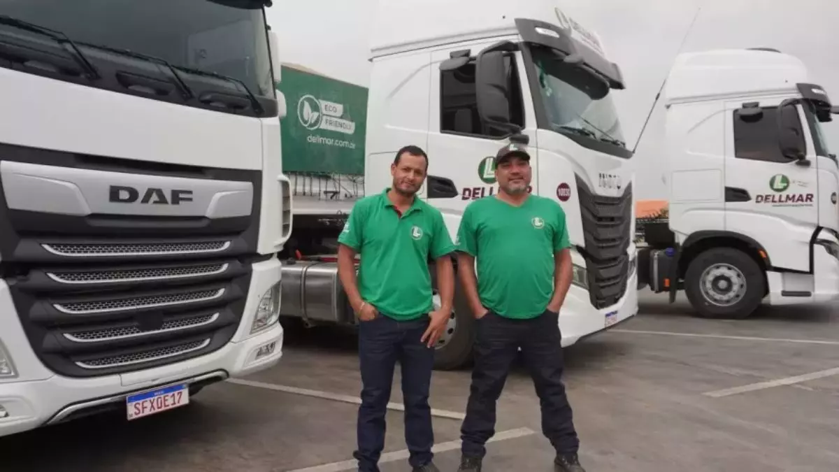 A foto mostra uma frota de carretas e dois motoristas da Dellmar Transportes