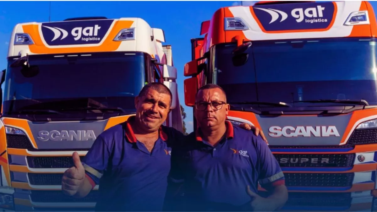 A foto mostra dois caminhões e dois motoristas da GAT Logística