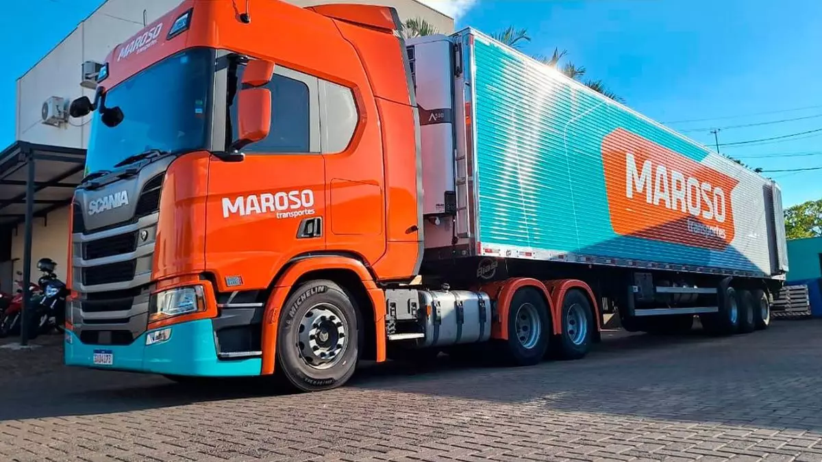 A foto mostra uma carreta azul e laranja da Transportes Maroso