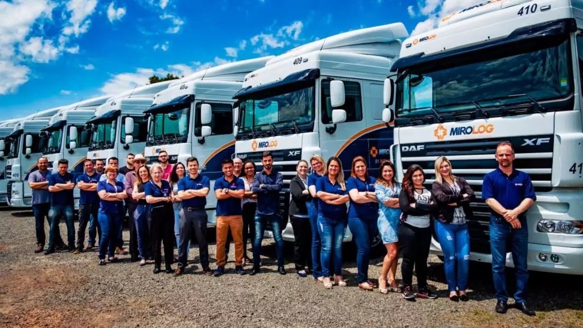 A foto mostra uma frota de caminhões e funcionários da MiroLog Transportes