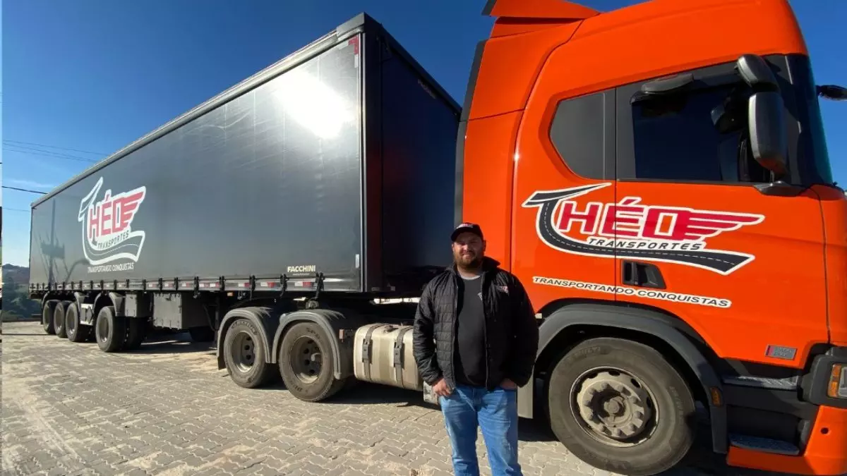 A foto mostra uma carreta e um motorista da Théo Transportes