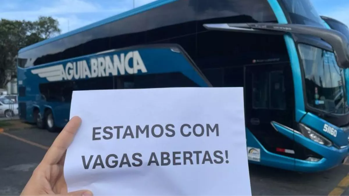 A foto mostra um ônibus do Grupo Águia Branca e um papel mostrando a frase "Estamos com vagas abertas".