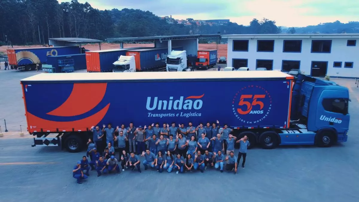 A foto mostra uma carreta e vários funcionários da Unidão Transportes