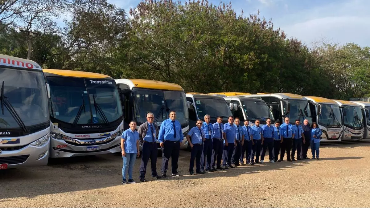 A foto mostra uma frota de ônibus e motoristas da Transmimo