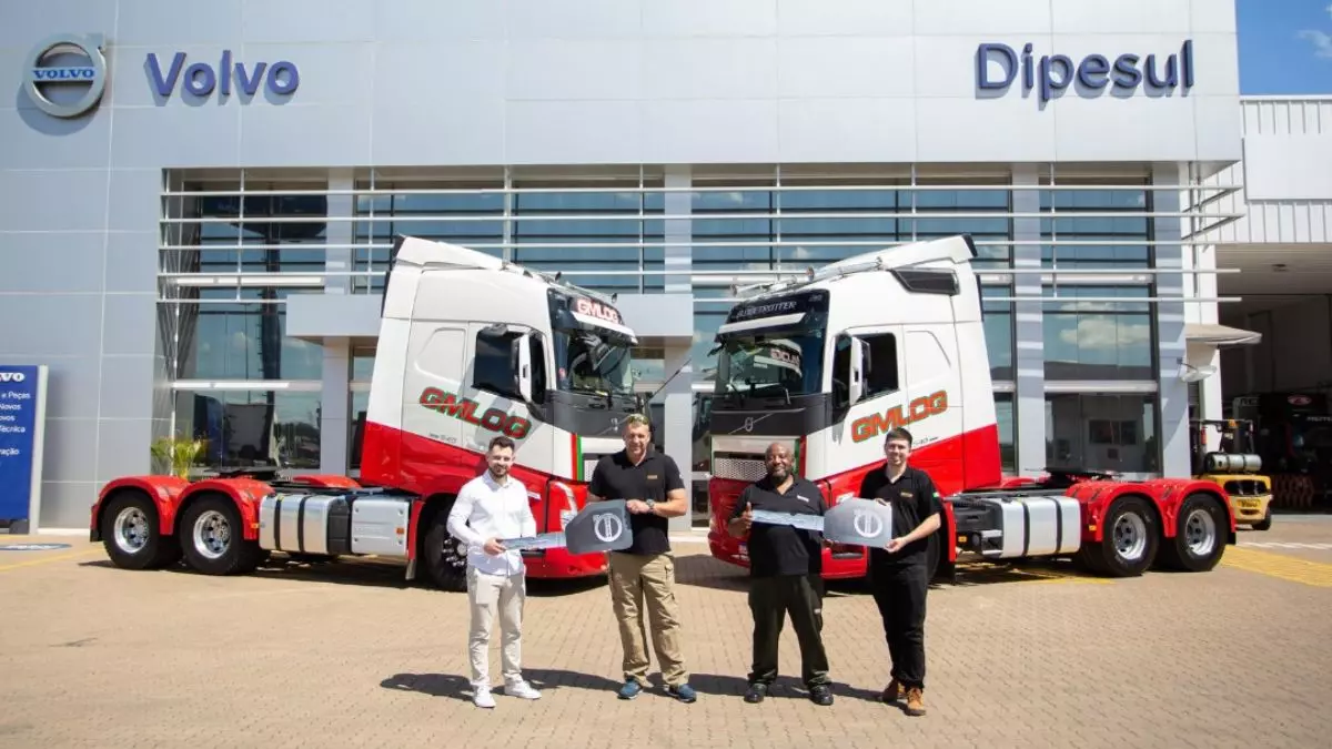 A foto mostra 2 caminhões da Gmlog Transportes e 4 pessoas