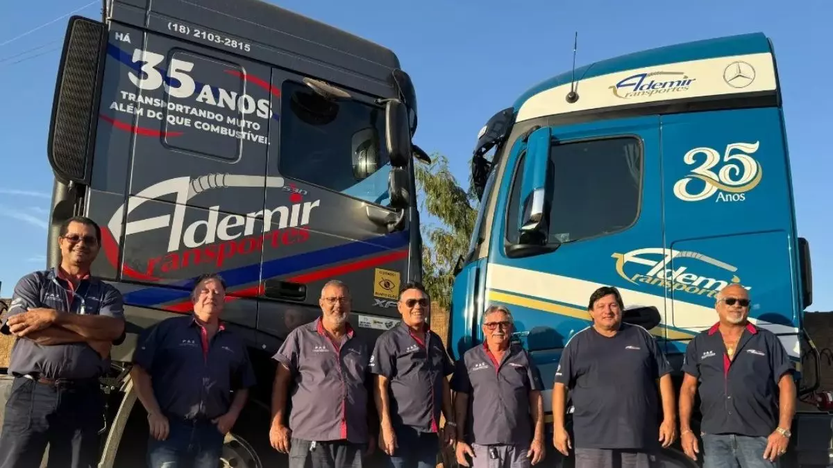 A foto mostra dois caminhões e vários motoristas da Ademir Transportes
