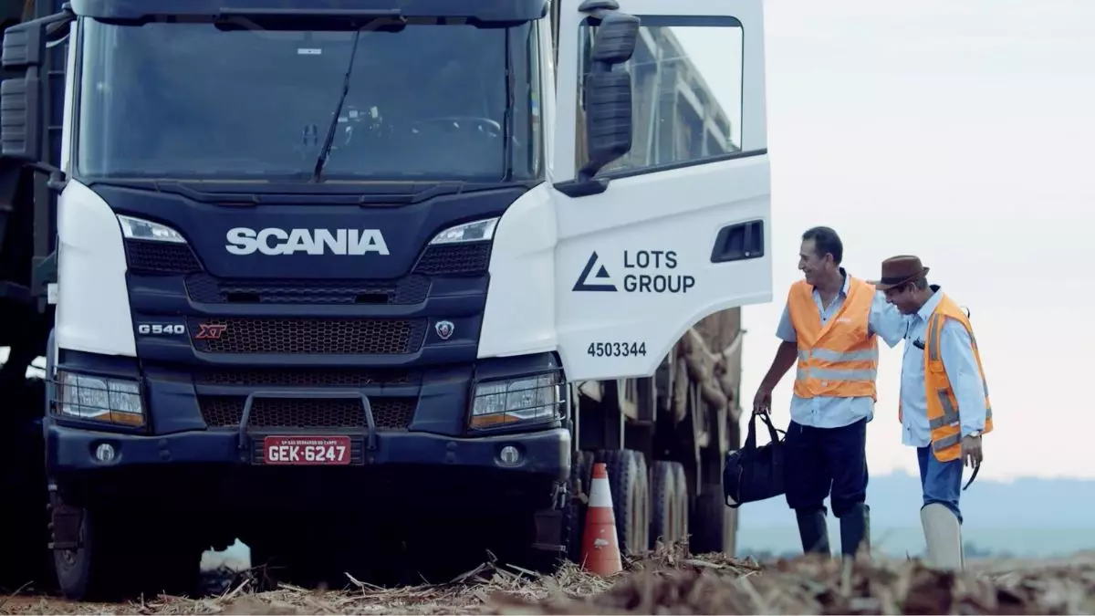 A foto mostra um caminhão da LOTS Group e 2 motoristas