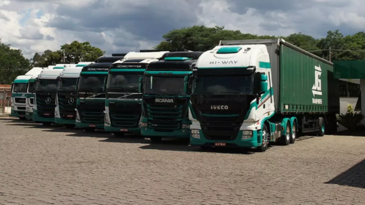A foto mostra uma frota de caminhões e carretas da JG Transportes