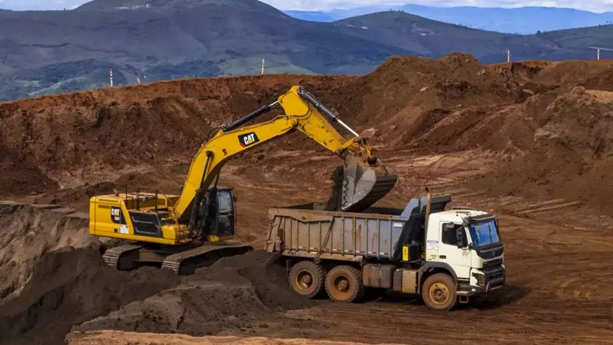 A foto mostra um caminhão traçado e uma escavadeira da Mineração Serra da Moeda